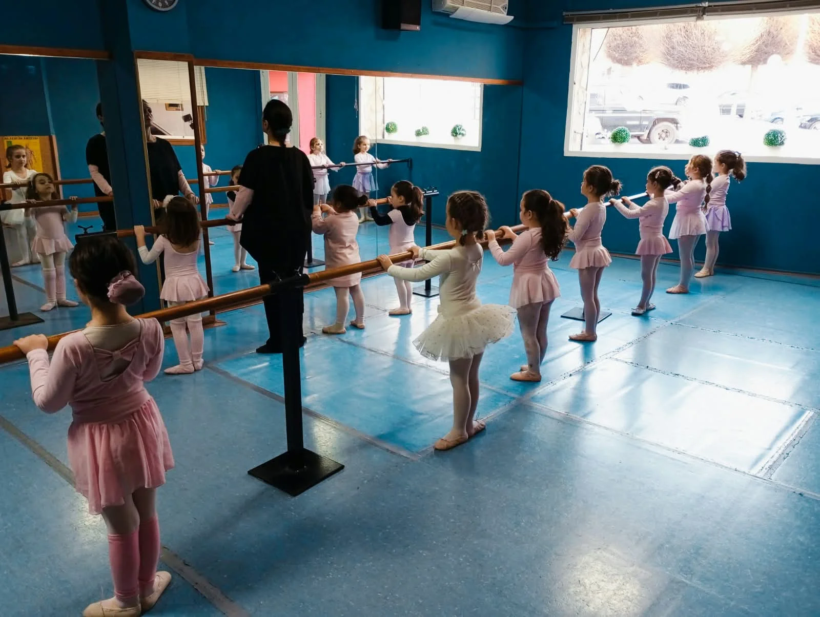 Una clase infantil de danza practica en la barra de la escuela